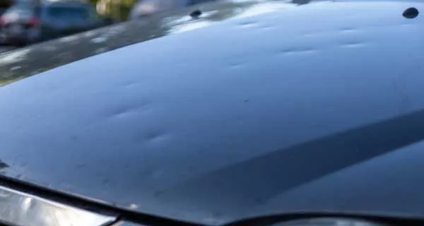 Hail-damaged car roof and hood awaiting repair