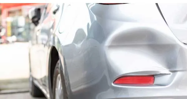 Damaged front bumper and fender being assessed for repair